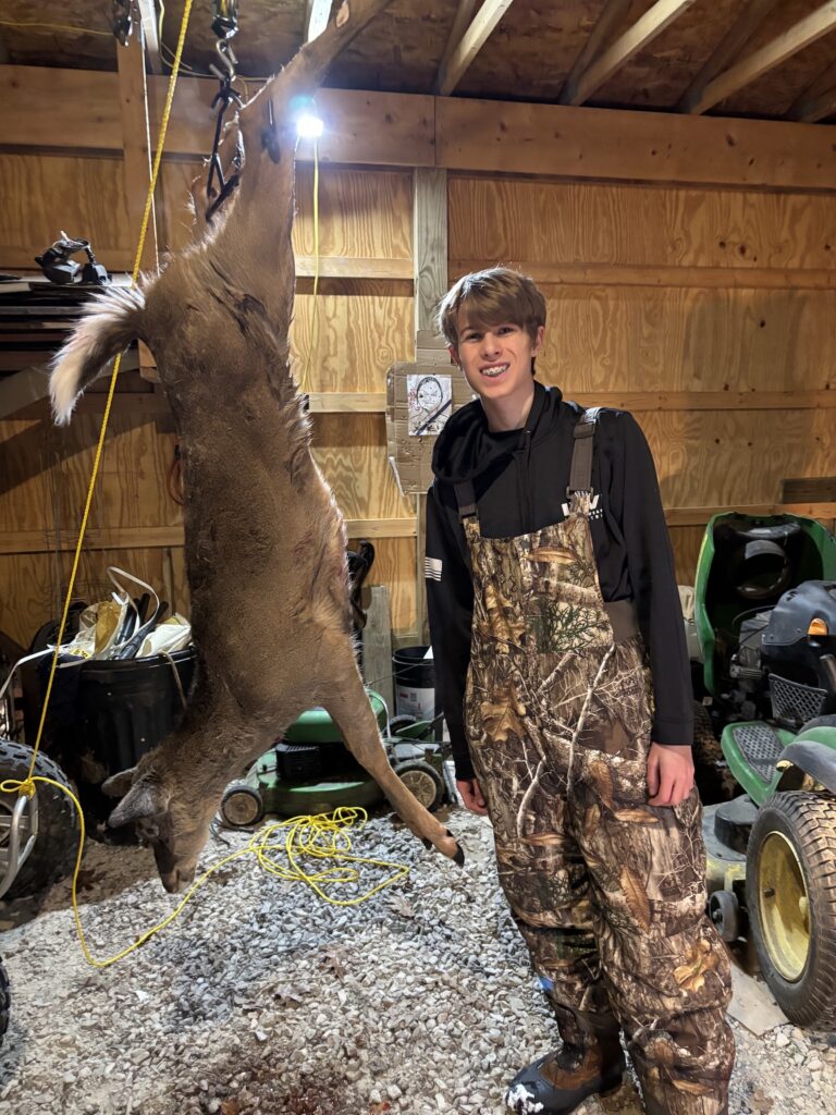 Boy in front of hanging deer