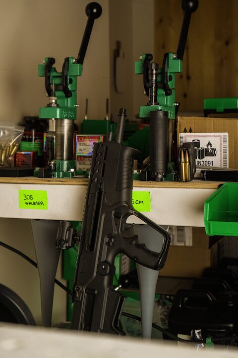 rifle leaning against bench with reloading tools