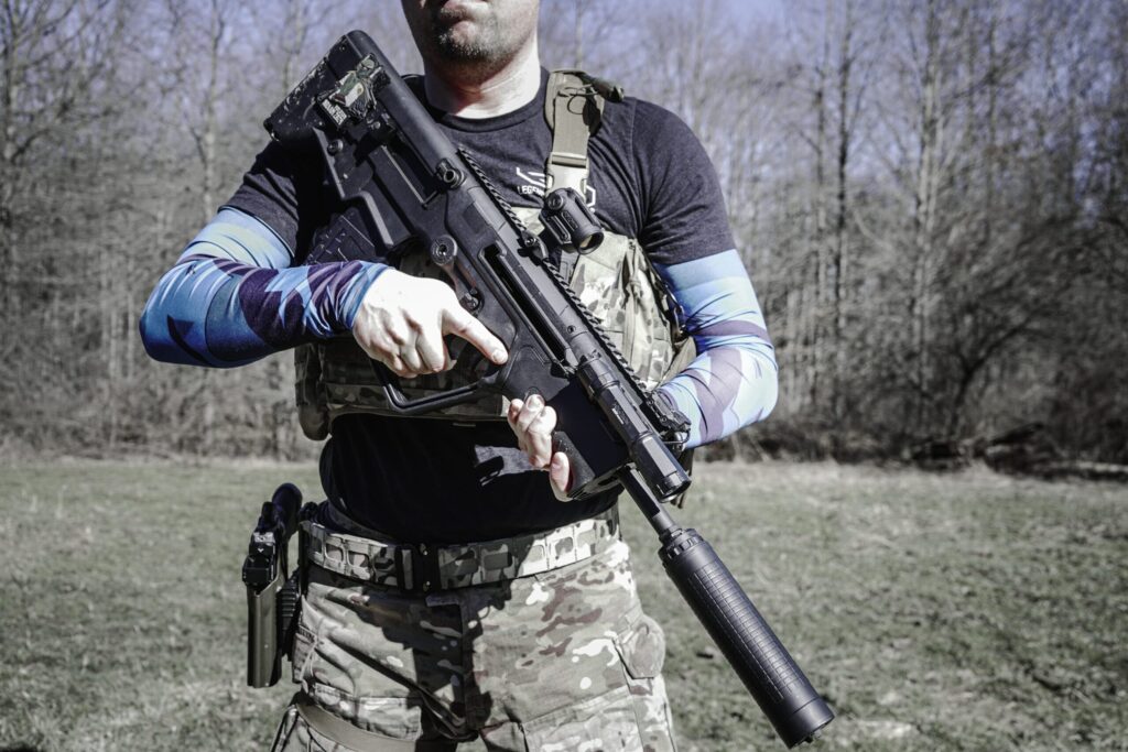 man holding suppressed rifle