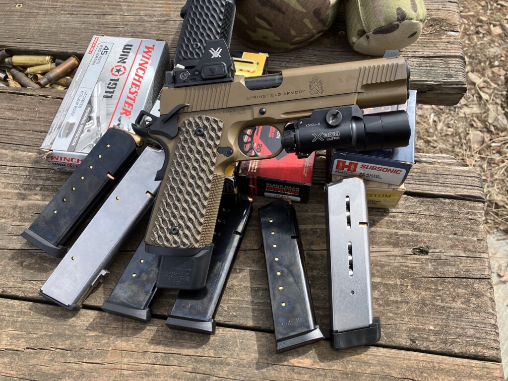 Pistol on shooting bench outdoors with magazines and ammo