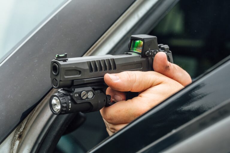 hand holding gun by car