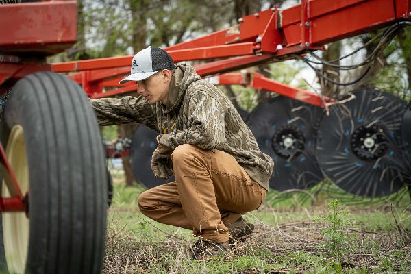 man kneeling by tractor