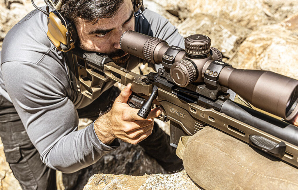 Man set in shooting position with rifle set on rocks