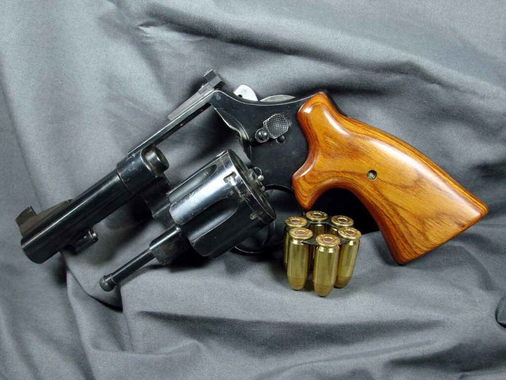Revolver on grey backdrop with cylinder open and ammunition set in front