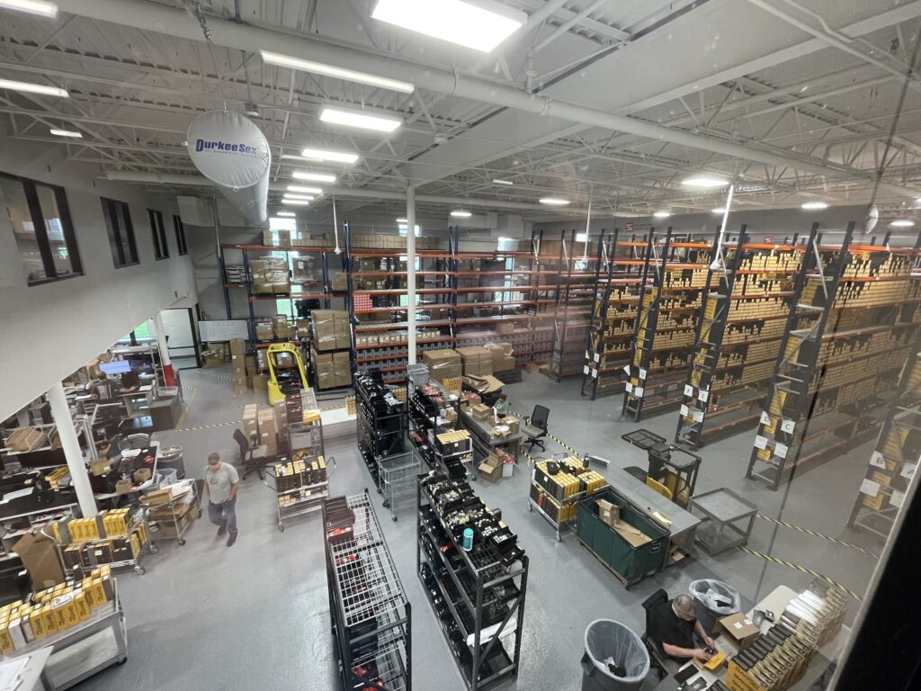 Boxes sitting on shelves with worker around in warehouse