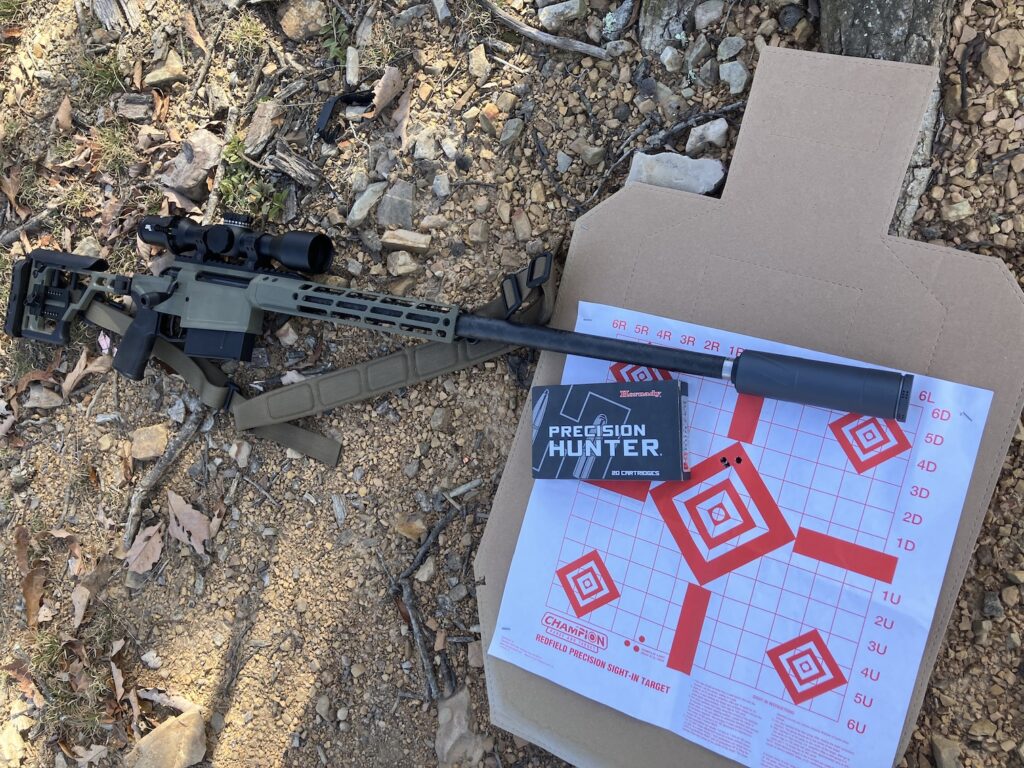 suppressed rifle in front on target and ammunition box on ground