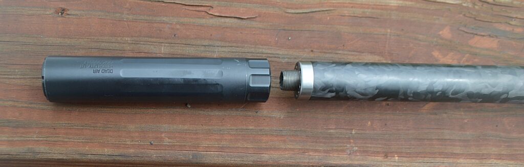 suppressor detached from rifle barrel on wooden table