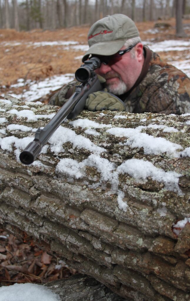 Rifle brace on tree while held by man in woods