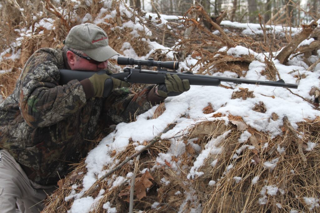 Man by trees holding rifle