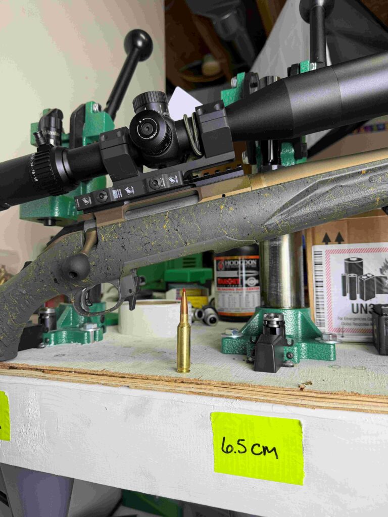 6.5 Creedmor ammo shown with bolt action rifle in background 